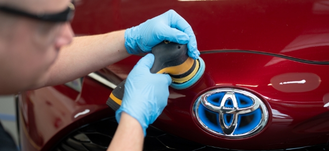 Mechanik polerujący maske samochodu